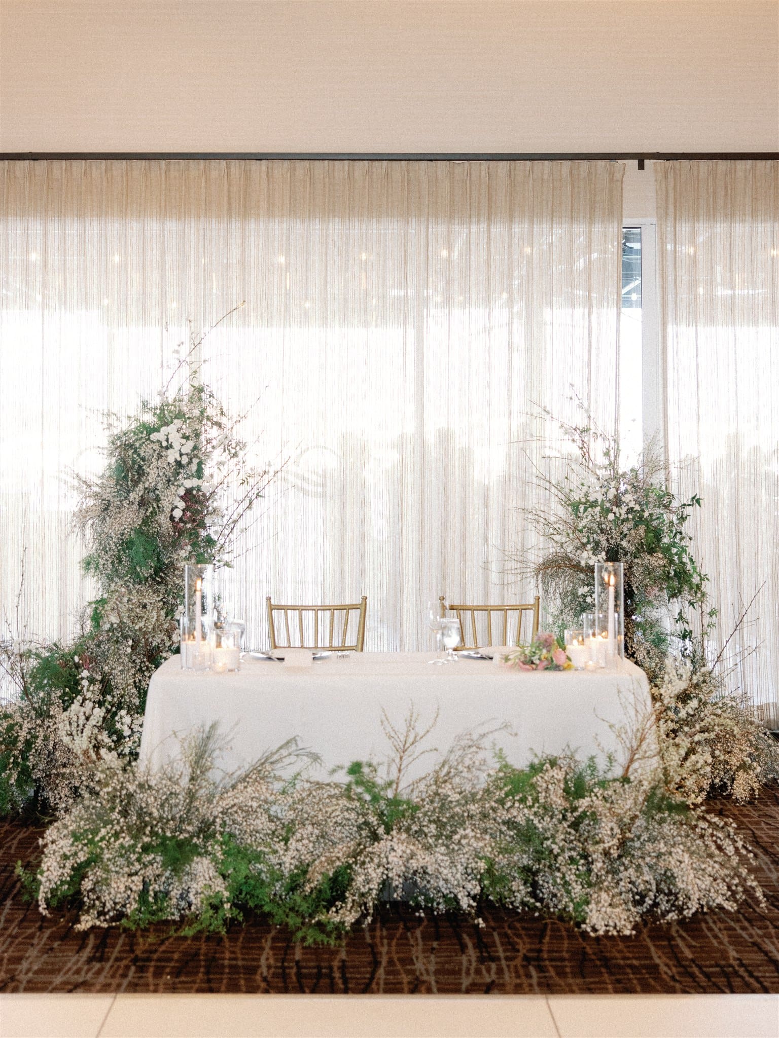 Wedding sweetheart table with white florals and greenery