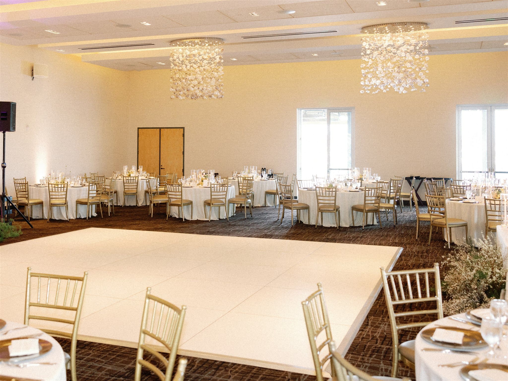 Wedding reception room with ivory linens and gold chiavari chairs