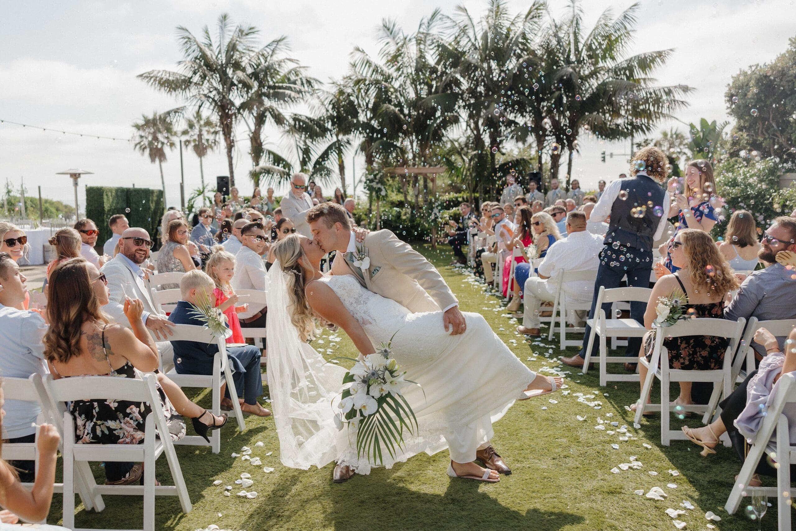 Bride and groom kiss in wedding aisle at Cape Rey ceremony
